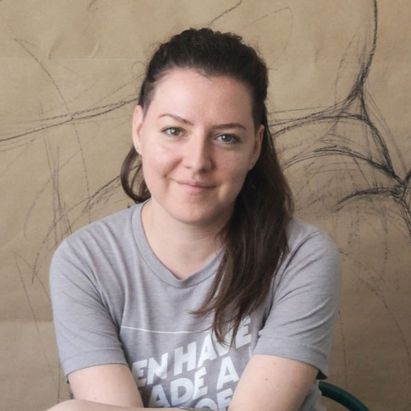 Andra sitting in front of a large drawing and smiling