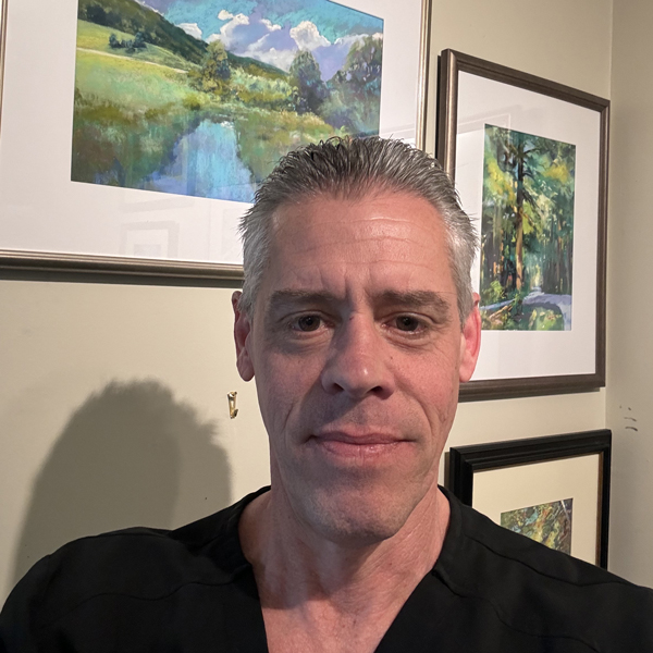 Fred Fielding standing with framed pastels behind him